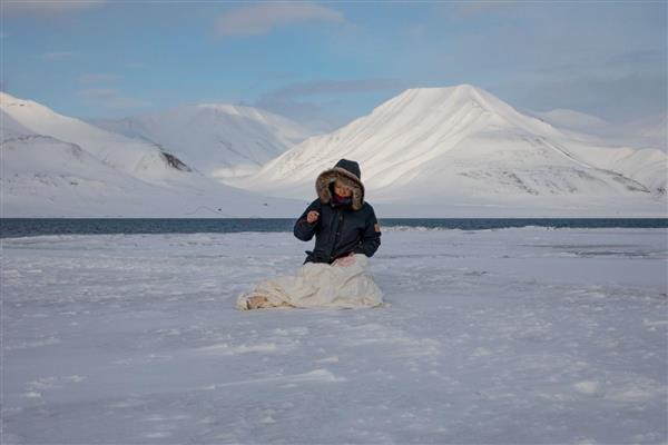 Kunstnaren Beili Liu medan ho syr på ein tekstil. Omgitt av snø og is. 